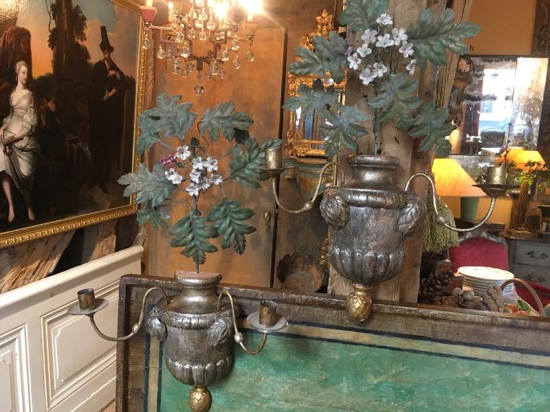 Paire d’appliques à 2 branches en bois sculpté argenté surmontées d’un feuillage en tôle peinte